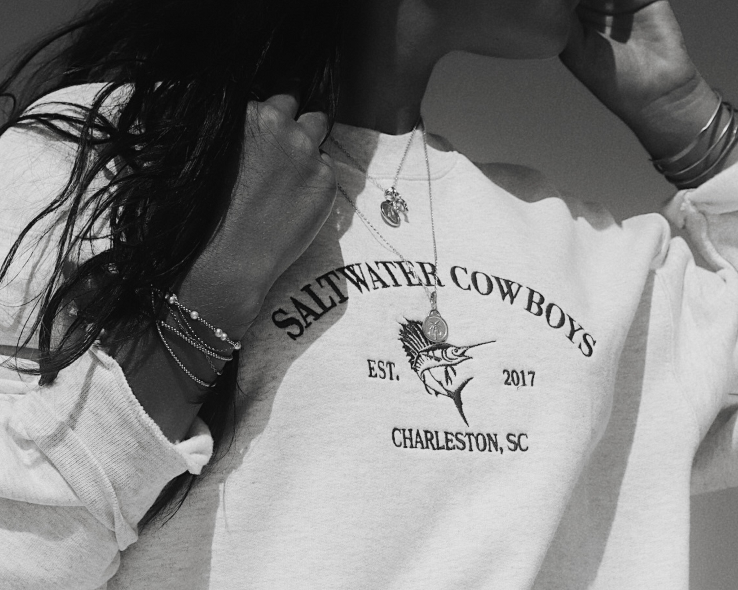 White sweatshirt with 'Saltwater Cowboys' branding worn by a person.
